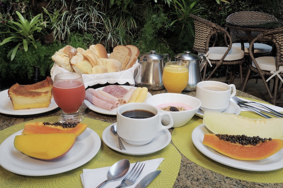 Mesa de café da manhã com frutas, bolos e bebidas
